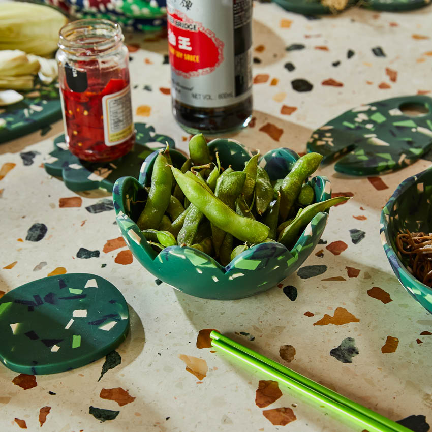 The Sage x Clare Petal Bowl in Pine Terrazzo with edamame in it on a table setting