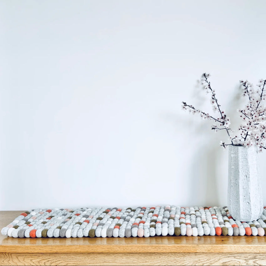 SHEEP-ish Design Felt Table Runner in Light Multi on a table with a vase with blossoms in it