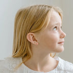 The Silver Linings Collective Daisy Kids Earrings on a girls ears
