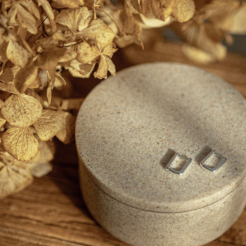 The Silver Linings Collective Marle Earrings in Silver on a textured trinket box next to flowers