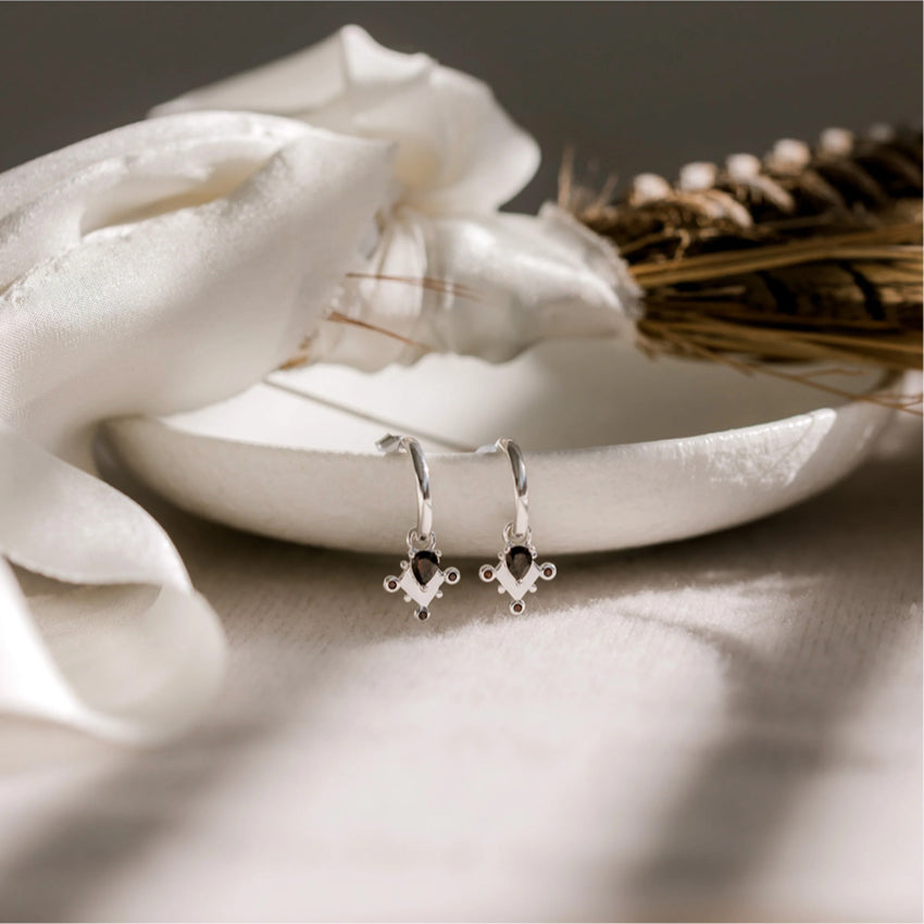 The Silver Linings Collective Monarchy Hoops in Silver hanging over a bowl