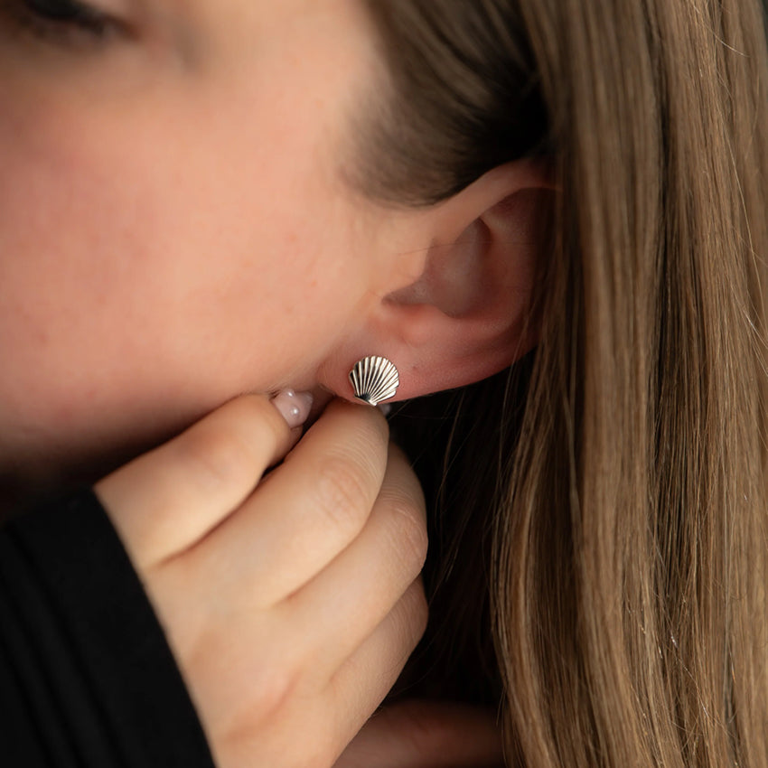 The Silver Linings Collective Shell Studs in Silver on a models ear