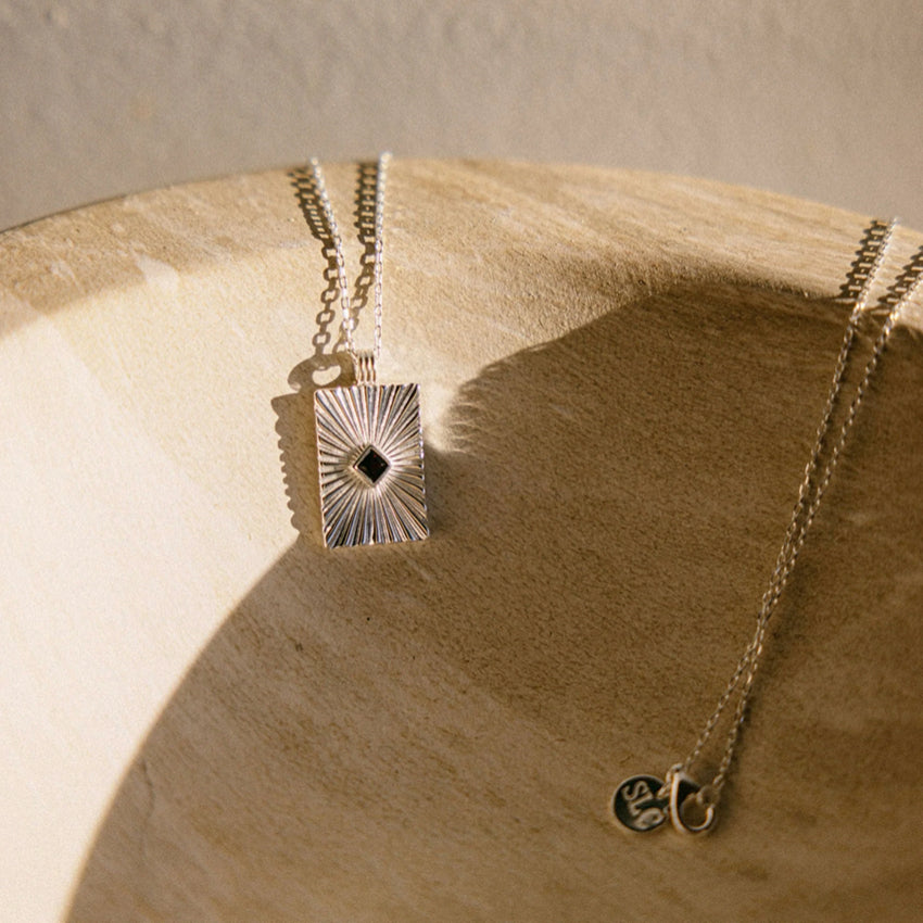 The Silver Linings Collective Verity Necklace in Silver on a textured bowl