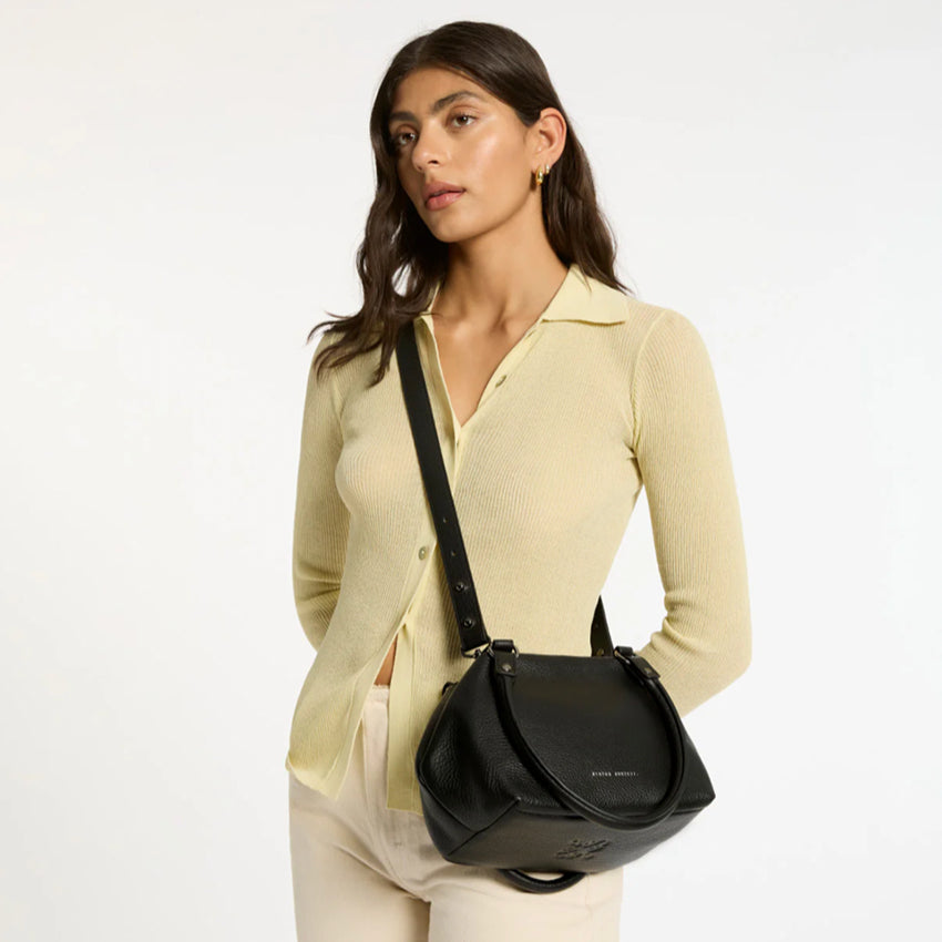 A model wearing the Status Anxiety Astral Bag in Black crossbody on a blank background