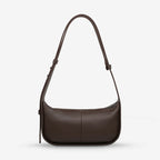 A back view of the Status Anxiety Haven Bag in Cocoa on a grey background