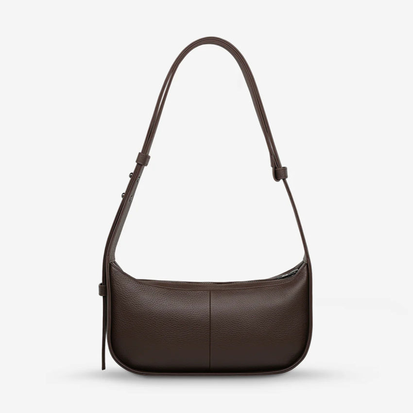 A back view of the Status Anxiety Haven Bag in Cocoa on a grey background