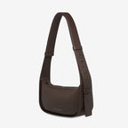 A side view of the Status Anxiety Haven Bag in Cocoa on a grey background