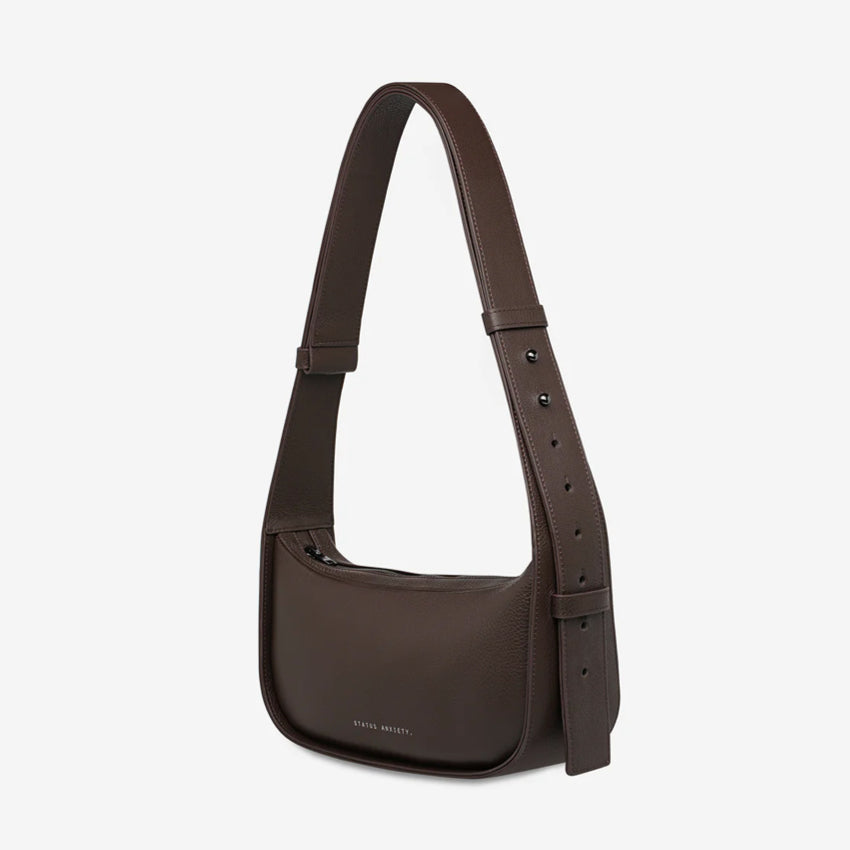 A side view of the Status Anxiety Haven Bag in Cocoa on a grey background