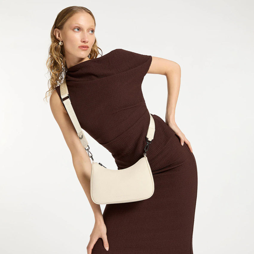 A model wearing the Status Anxiety Look Both Ways Bag in Chalk across her body