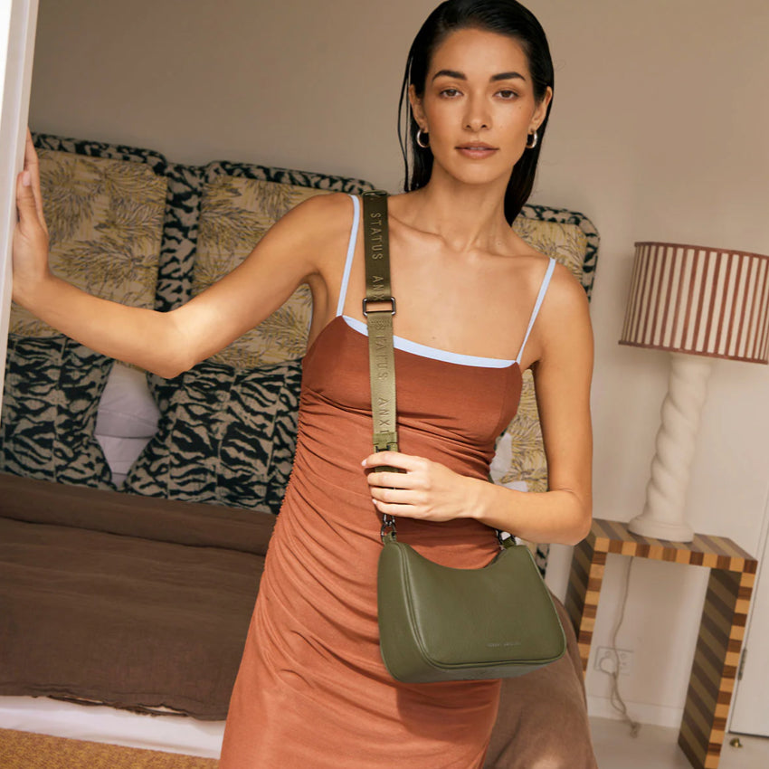 The Status Anxiety Look Both Ways Bag in Khaki crossbody on a model in a house