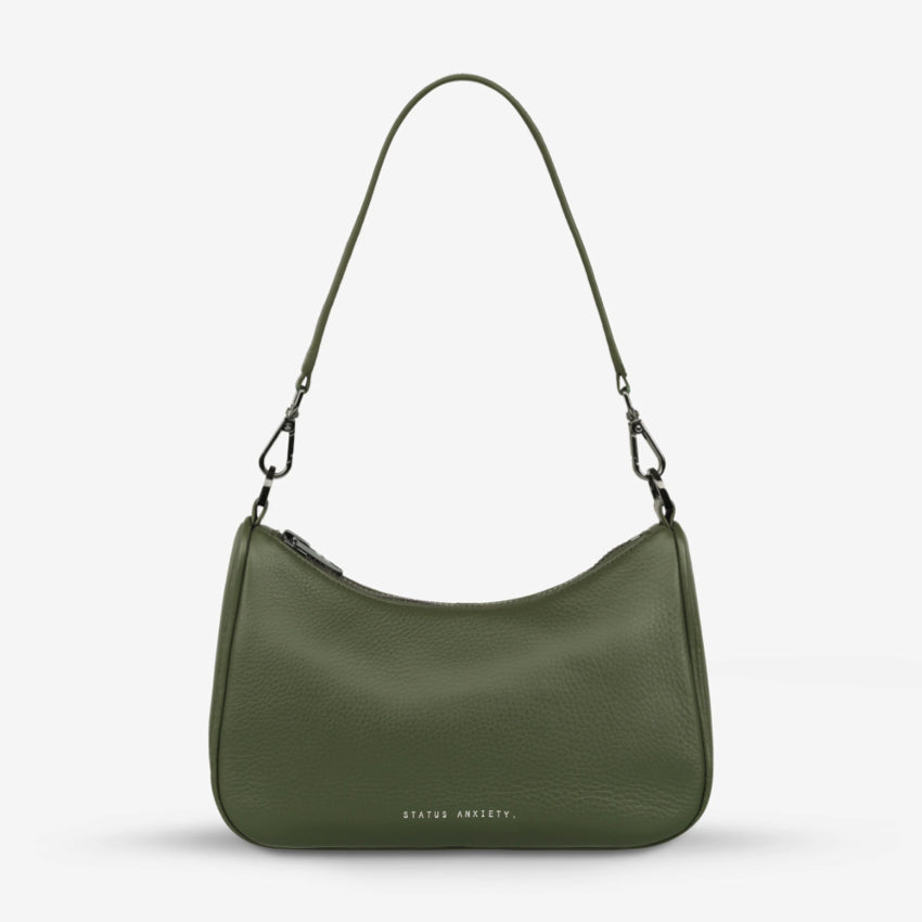 The Status Anxiety Look Both Ways Bag in Khaki with just the shoulder strap on on a grey background