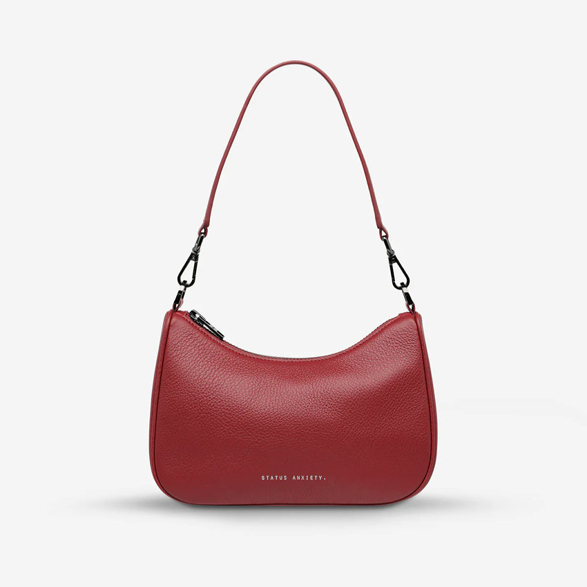 The Status Anxiety Look Both Ways Bag in Rouge on a grey background with the short strap on 