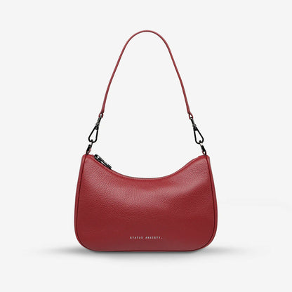 The Status Anxiety Look Both Ways Bag in Rouge on a grey background with the short strap on 