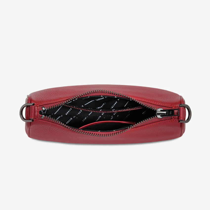 An inside view of the Status Anxiety Look Both Ways Bag in Rouge on a grey background