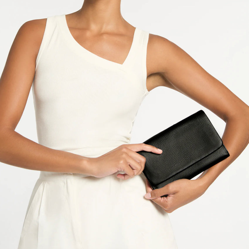 A model holding the Status Anxiety Remnant Wallet in Black on a blank background
