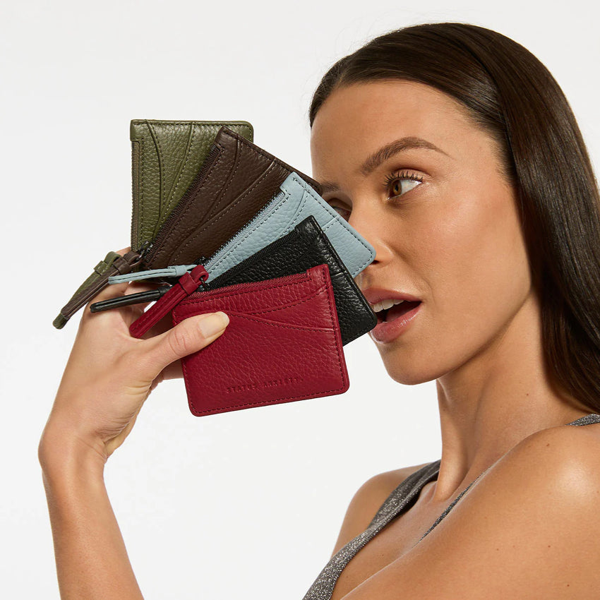 A model holding 5 of the Status Anxiety Hearts Still Beating Wallet in different colours