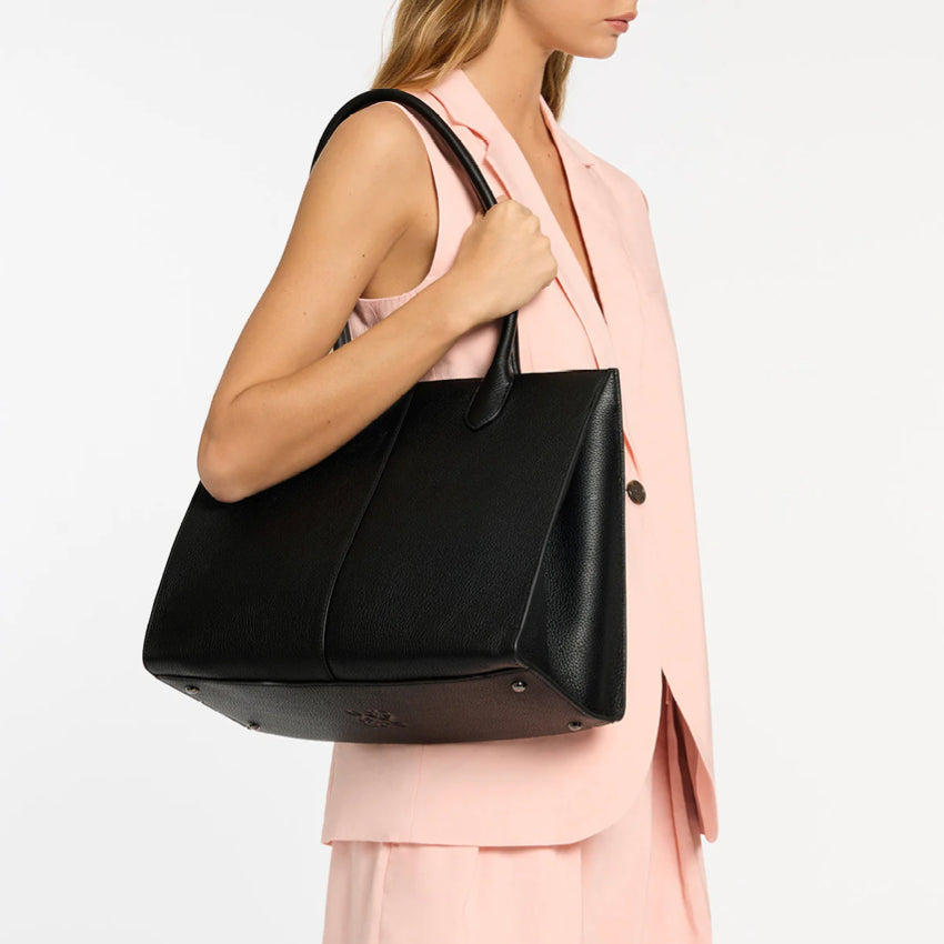 The Status Anxiety Without Warning Bag in Black on a models arm on a grey background