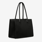 A side view of the Status Anxiety Without Warning Bag in Black on a grey background