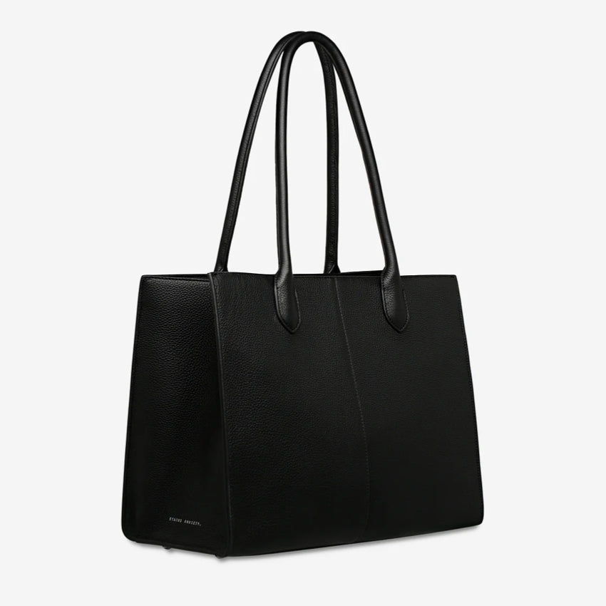 A side view of the Status Anxiety Without Warning Bag in Black on a grey background