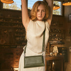 A model wearing the Status Anxiety Zenith Bag in Khaki in a workshop