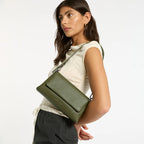 A model wearing the Status Anxiety Zenith Bag in Khaki on the short strap on a blank background