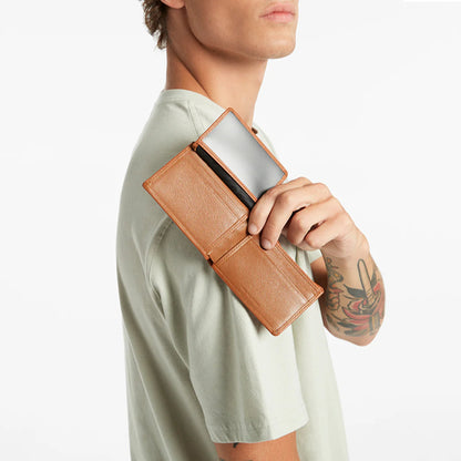 The Status Anxiety Jonah Wallet in Tan with a model holding it open