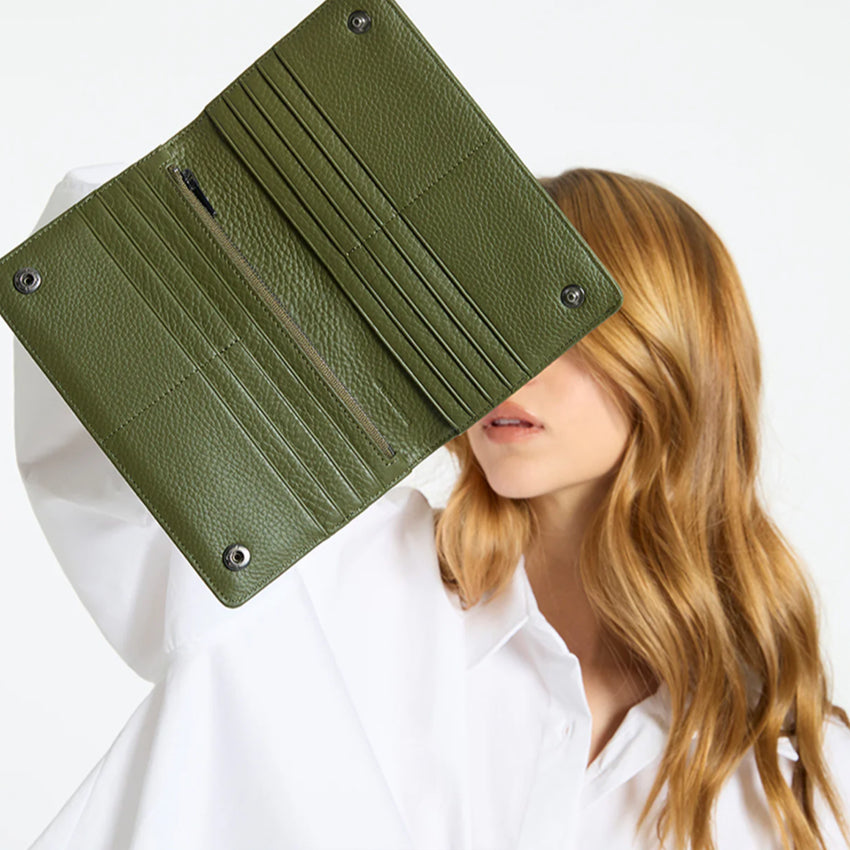 A model holding the Status Anxiety Living Proof Wallet in Khaki open