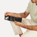The Status Anxiety Noah Wallet in Black with a model holding it