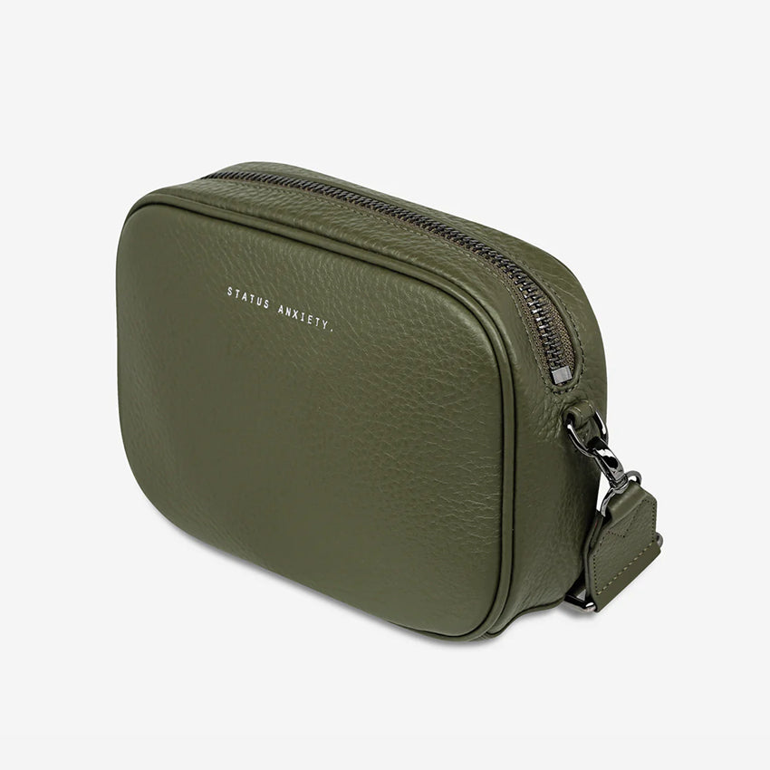 A side view of the Status Anxiety Plunder Bag with a Webbed Strap in Khaki on a blank background