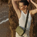 The Status Anxiety Plunder Bag with a Webbed Strap in Khaki on a model at a beach