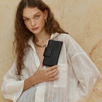 The Status Anxiety Ruins Wallet in Black with a model holding it 