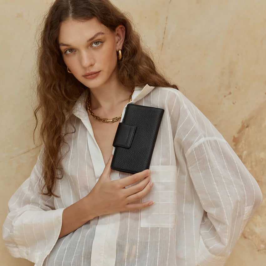The Status Anxiety Ruins Wallet in Black with a model holding it 