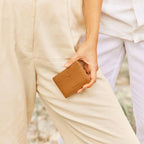 The Status Anxiety Together For Now Wallet in Tan with a model holding it