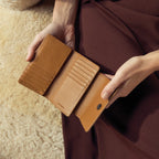 The Status Anxiety Visions Wallet in Tan with a model holding it open