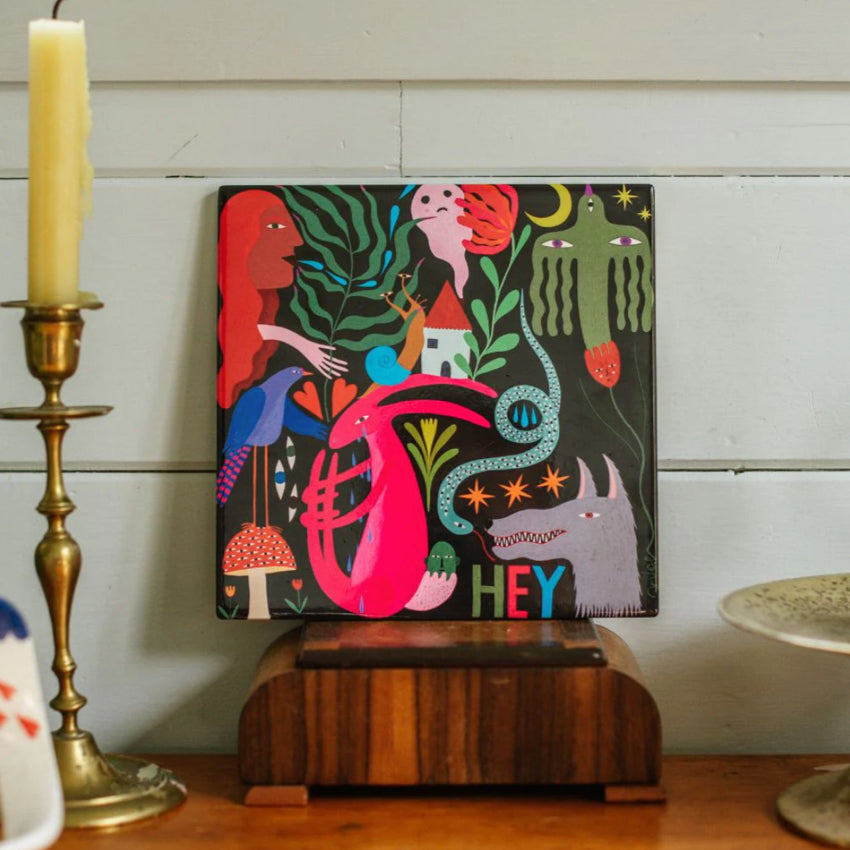 Studio Soph Hey Art Tile on a shelf next to a candle
