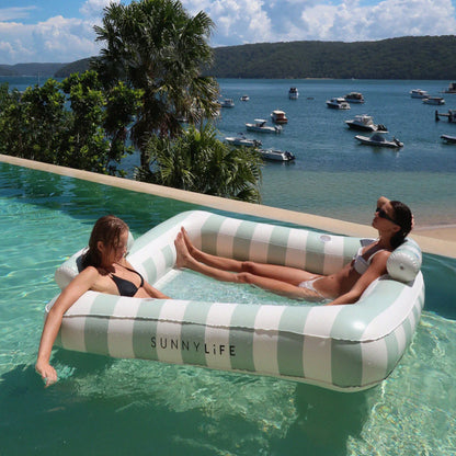 The SunnyLife Deluxe Twin Hammock in The Vacay in a pool with girls in it with boats in the background
