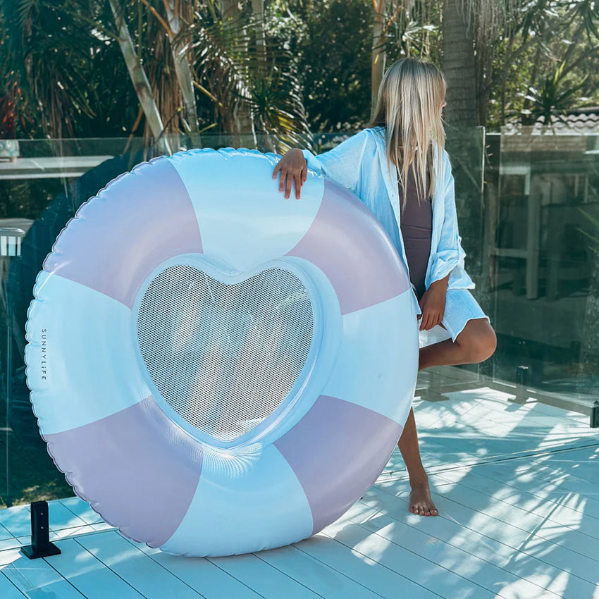 The Sunny Life Luxe Pool Ring in Stole My Heart leaning up against a glass pool fence