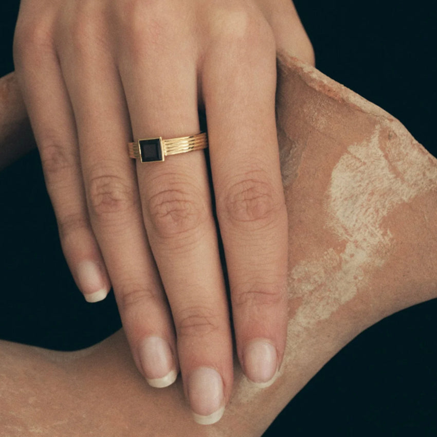 The Temple Of The Sun Sparta Ring in Gold on a models hand also holding a ceramic