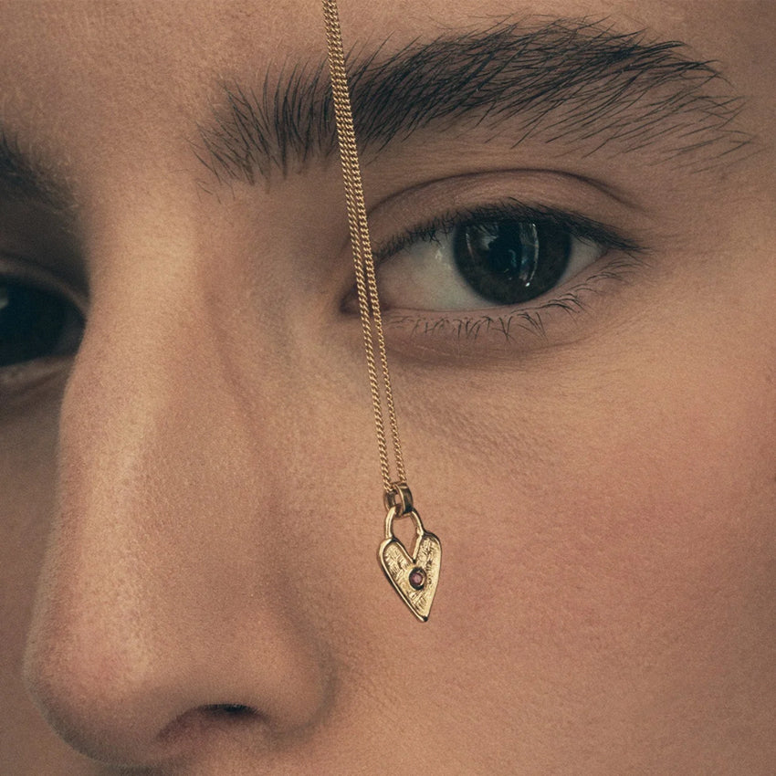The Temple Of The Sun Amore Necklace in Gold Vermeil held in front of a models face