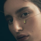 The Temple Of The Sun Etti Necklace in Gold Vermeil held up to a models face