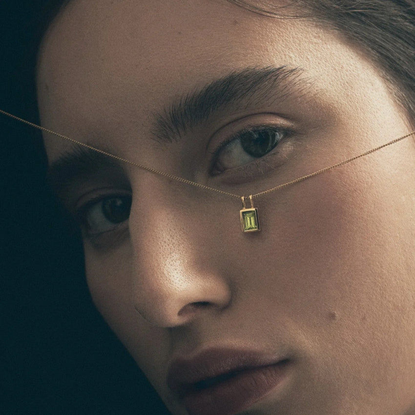 The Temple Of The Sun Etti Necklace in Gold Vermeil held up to a models face