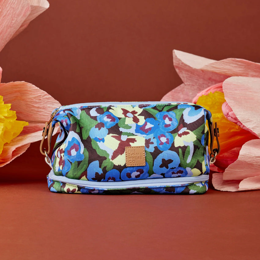 The Somewhere Co Cosmetic Bag in Pansy Path next to craft flowers