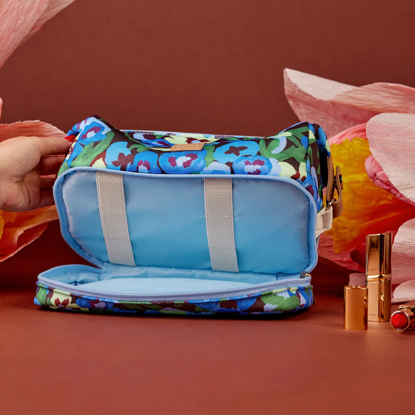 The Somewhere Co Cosmetic Bag in Pansy Path open next to craft flowers