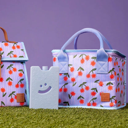 The Somewhere Co Lunch Bag in Sunburst on grass next to a icepack 