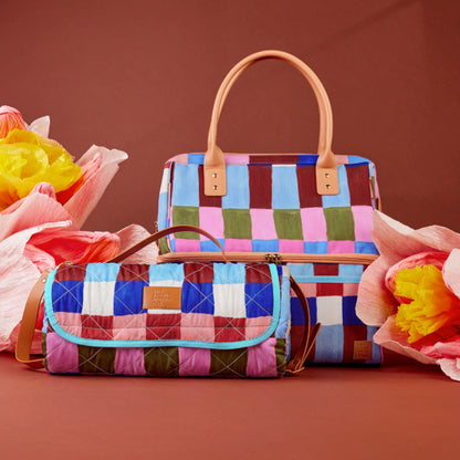 The Somewhere Co XL Picnic Rug in Hopscotch next to a matching cooler bag next to flowers