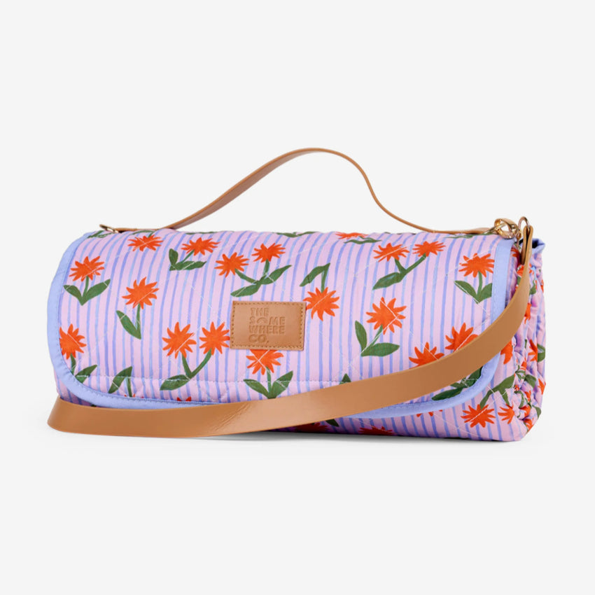 The Somewhere Co XL Picnic Rug in Sunburst rolled up on a grey background