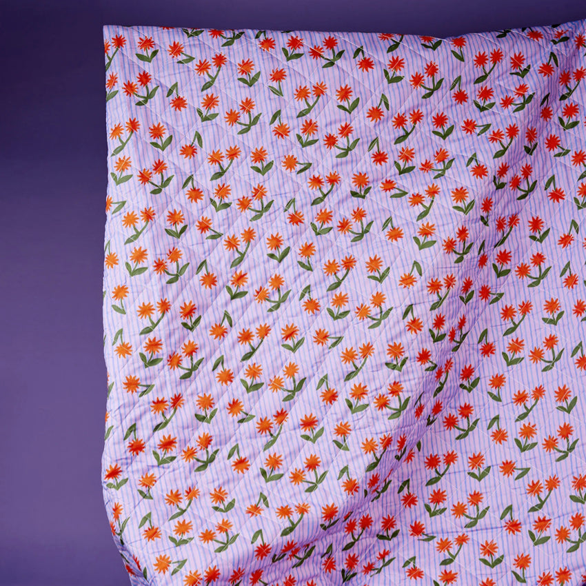 The Somewhere Co XL Picnic Rug in Sunburst held up on a purple background