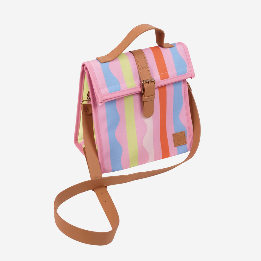 The Somewhere Co Lunch Satchel in Sweet Siesta pattern with its long strap on it on a blank background