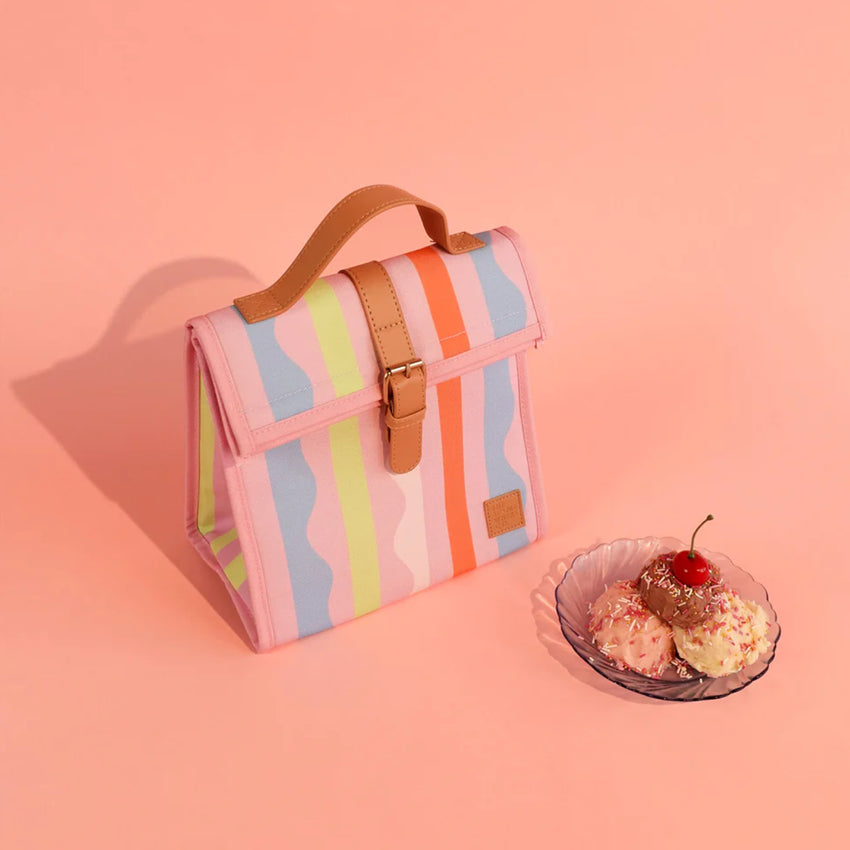 The Somewhere Co Lunch Satchel in Sweet Siesta on a peach backdrop next to an icecream sundae