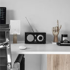The Tivoli Audio Model One BT in Black and Black on a desk 